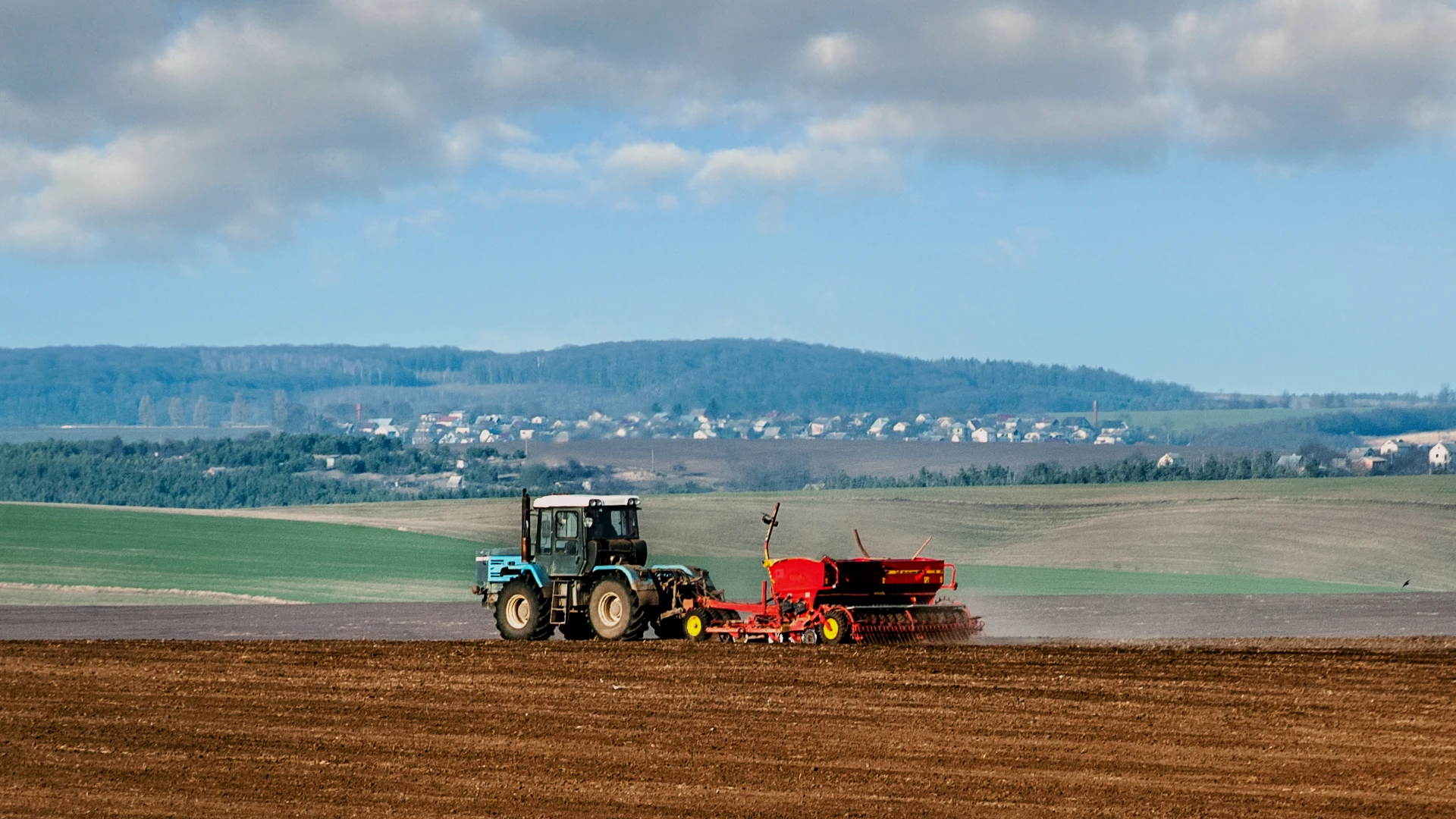Tractor pulling a seed drill across a cultivated field